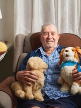 Carinity Brookfield Green aged care resident Stan Fryer with two robotic companion pets